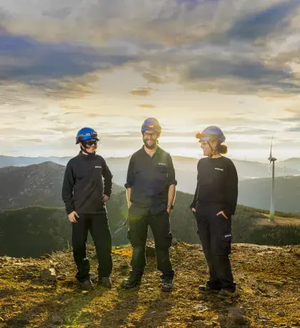 Techniciens et techniciennes face à une éolienne