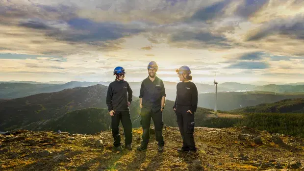 Techniciens et techniciennes face à une éolienne