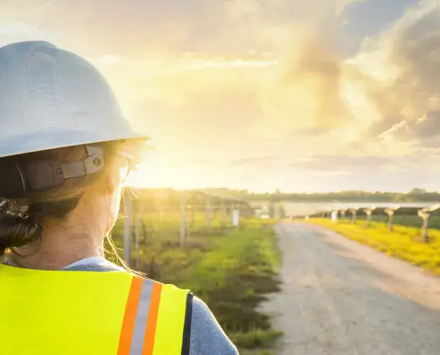 Technicienne faisant face à des panneaux solaires et un couché de soleil
