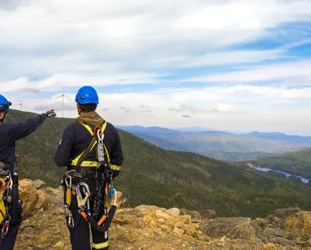 Techniciens et techniciennes face à une éolienne